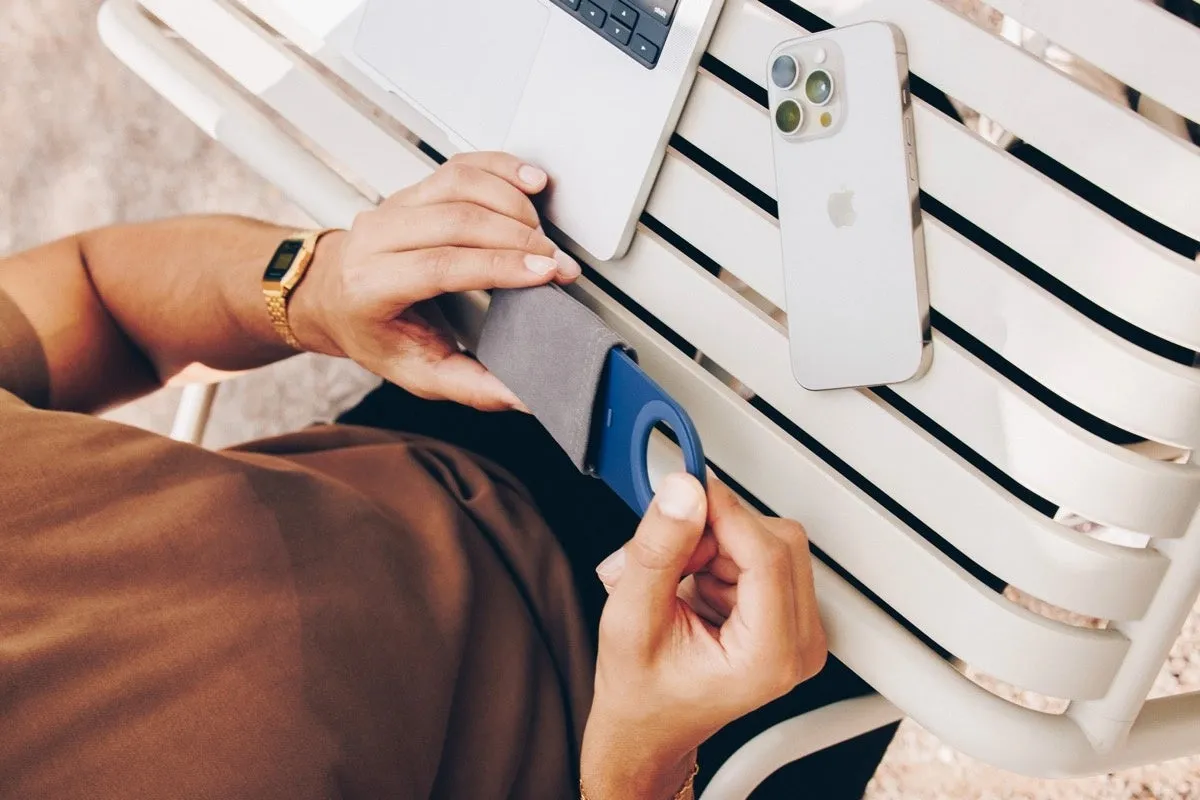 テーブルの上に置かれたiPhoneと、財布から取り出される青い充電器を持つ人のクローズアップ写真。